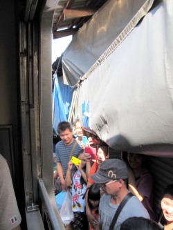Tourists standing in between the market stalls and the running train